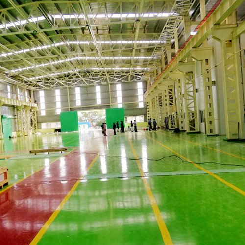 Green and red epoxy flooring with safety lanes in a manufacturing hall